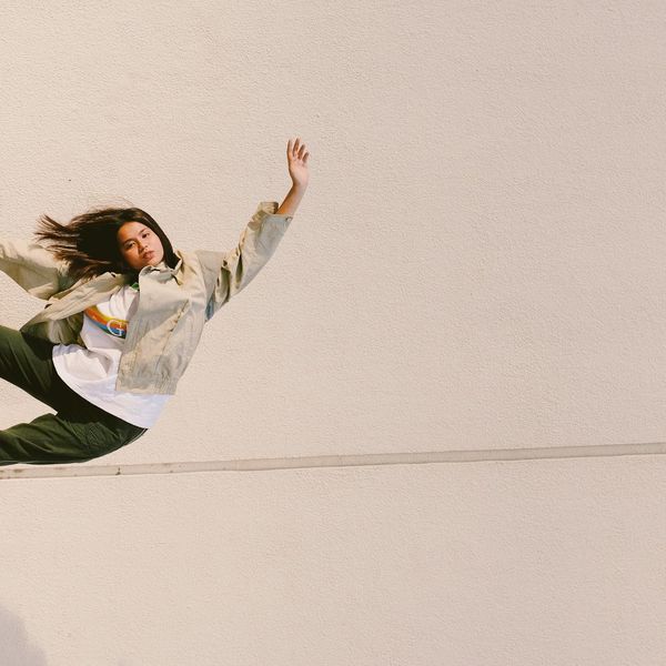 Person doing a flowing yoga movement against a dark, minimalist background.